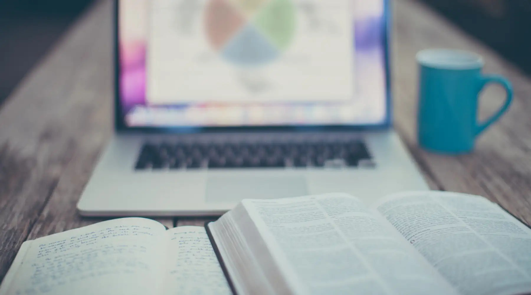 Open white pages of a book resting on a wooden table.