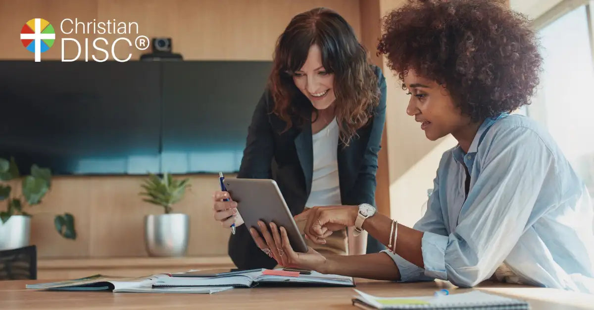 Silver tablet with a sleek, modern design held by two women in an office setting.