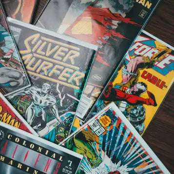 A stack of colorful comic books featuring bold artwork and titles like ’silver surfer’ and ’cable,’ with covers in vibrant hues including red, yellow, black, and blue.